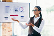© deagreez - Successful businesswoman presenting analytics and strategy solutions in an office with a screen displaying visual data charts