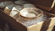 © thenort - Packaged delicate porcelain plates and bowls in a cardboard box with bubble wrap for safe moving or storage.