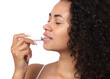 © New Africa - Smiling woman applying lip balm onto her lips on white background, closeup