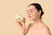 © Pixel-Shot - Young woman with bath bombs and plumeria flowers on beige background, closeup