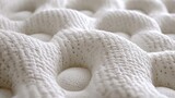 Close-up view of a mattress's textured surface. A soft, white, knitted material with raised, rounded bumps and small holes