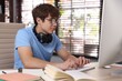 © New Africa - Teenage student with headphones using computer while studying at table indoors