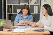 © Thitisak - Two Asian businesswomen are having a meeting and discussing their work.