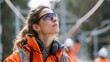 © Mrammon - A woman wearing an orange jacket and goggles is looking up at something
