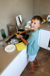 © Natallia - Smiling Boy Washing Dishes at Sink