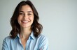 © starush - Woman smiling with arms crossed wearing a light blue shirt against a plain background