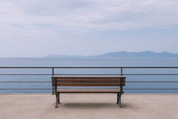 Wall Mural - Scenic view of calm ocean with distant mountain landscape behind a seaside promenade bench.