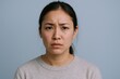 © Generative AI - Portrait of an Asian woman with skeptical serious facial expression on plain background.