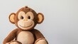 © Othello - Cute brown plush monkey toy sitting against a light grey background.