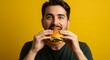 © Yusof - Young man enjoying a burger against a vibrant yellow background. Suitable for fast food, lifestyle, and advertising concepts. Colorful and expressive.
