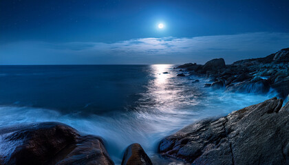 Wall Mural - serene night ocean waves flowing over bold rocky coastline under illuminating moonlight with smooth reflection on calm waters