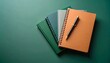 © YNG - Colorful notebooks with pen stacked on green background for school or office use