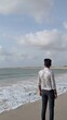 © AK47 - Man Standing on Beach Shore Looking at Ocean Under Cloudy Sky