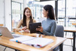 © SOMKID - Two Asian young businesswoman using laptop computer working in office,