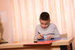 © Vasyl - A boy makes applications from colored paper while sitting at a table. The concept of creativity and leisure.