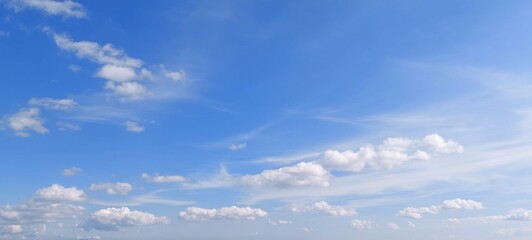 Wall Mural - Panoramic cloudscape in clear blue sky in summer. Nature sky background with fluffy clouds.