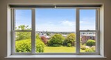Scenic garden view through large window overlooking suburban neighborhood