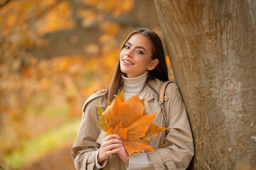 Wall Mural - Portrait of young woman with autumn leafs. Romantic girl dream, hold fall maple leaves. Autumnal season.