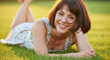 © Ayase - Cheerful Woman Relaxing on Green Grass Smiling Outdoors on a Sunny Day