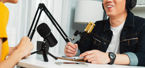 Smiling radio influencer host wearing headphone interviewing woman speaker sharing information to listeners on social media online website live streaming channel at morning at studio record. Infobahn.