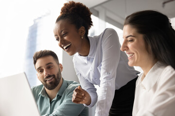 Marketing department preparing plan product launch or promotional event gathered together around modern laptop, review new software, watching presentation, engaged in effective, productive teamwork