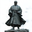 © btiger - Detailed statue of a stern man wearing traditional robe standing confidently on rough rock base with solemn expression and flowing garment