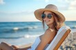© Margarita - Smiling woman wearing sunglasses and a wide-brimmed straw hat relaxing on a beach chair by the ocean on a sunny day