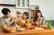 © NINENII - Smiling Asian family enjoying breakfast in weekend morning. parents and daughter, cooking, and sharing joyful at the dining table in the kitchen together.