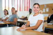 © JackF - Positive young woman attending lecture in classroom. Female student sitting at desk during lesson.