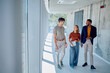 © we.bond.creations - Group of multi-ethnic businesspeople walking and engaging in conversation while enjoying a break in a modern office corridor