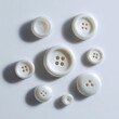 © KASUEMA SALAE - A collection of diverse-sized white buttons, scattered, isolated on a pure white background. Sewing, craft, texture.