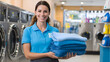 © utaem2022 - Laundromat worker holding clean towels smiling at the self service laundry