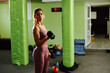 © djile - Determined sportswoman lifting dumbbells during intense workout session in gym