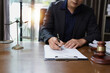 © SOMKID - Lawyer Businessman Working with Documents and Signing Contract at Office Desk.