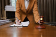 © SOMKID - Lawyer Holding Hammer with Document Paper on Wood table,  Law, Justice Symbol,