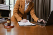 © SOMKID - Female Lawyer Working on Document Paper with Laptop and lawyer Hammer at Office Desk, Judge's Gavel, Law,