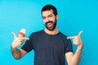 © luismolinero - Young man with a cornet ice cream over isolated blue background proud and self-satisfied