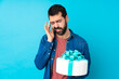 © luismolinero - Young handsome man with a big cake over isolated blue background with headache
