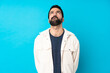 © luismolinero - Young handsome man with white corduroy jacket over isolated blue background and looking up