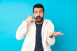 © luismolinero - Young handsome man with white corduroy jacket over isolated blue background making phone gesture and doubting