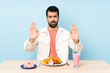 © luismolinero - Man at a table having breakfast waffles and a milkshake making stop gesture and disappointed