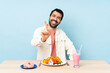 © luismolinero - Man at a table having breakfast waffles and a milkshake showing and lifting a finger