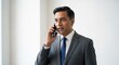 © Tadeu - Indian Businessman Talking on Mobile Phone with Focused Expression and Professional Attire Isolated on White Background