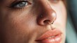 © Enigma - Close up of a young woman's face highlighting her nose piercing and natural freckles, capturing the beauty of individuality and self expression