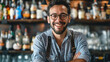 © Svetlana Leuto - Cheerful European male bartender smiling in uniform behind bar counter, mixing drink with bottles and glasses in background. Professional atmosphere