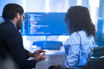 two diverse software developers celebrate a breakthrough, happily discussing a successful project. c