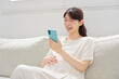 © siro46 - スマートフォンを使う妊婦　リビング