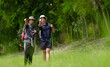 © Nassorn - Happy tourist hiking walking together over grassland of the plains. Active young adult man trekking through nature grass field over lowland in rural trail. Portrait of real people in peaceful meadow.