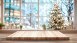 © mila103 - A wooden table sits in the foreground, while a beautifully lit Christmas tree adds warmth to the wintery backdrop. Soft lights twinkle outside the window, creating a cozy atmosphere.