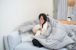© leungchopan - Woman lying sick under warm blanket at home